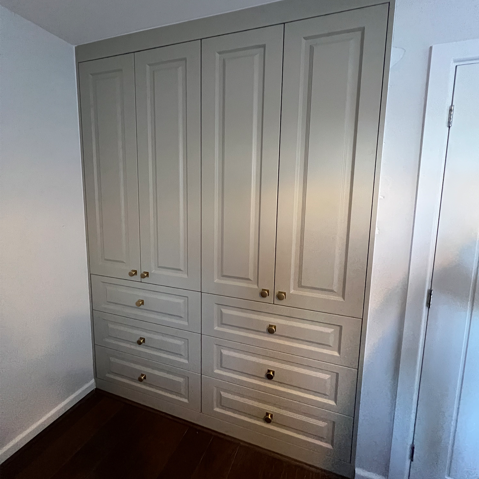 Elegant built‑in wardrobe with raised panel doors and brass accents